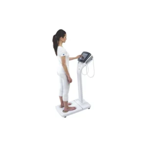 segmental-bia-body-composition-test-standing-device-2026 Person standing on a segmental bioelectrical impedance analyzer holding hand electrodes during body composition measurement.